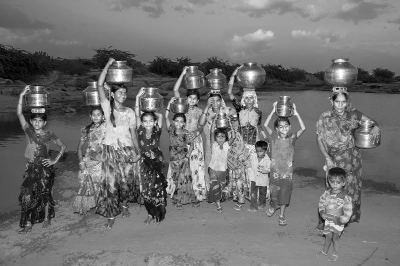 Human Right to Water in Kutch district, Gujarat - women and girls procuring water from a distant pond in the evening in a village in Kutch district that lacks public water supply. Despite the drudgery and the uncertainty of quality, they are happy that at least there is access to water